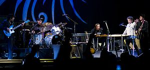 Dylan together with five members of his band onstage. Dylan, dressed in a white shirt and black pants, is second from right.