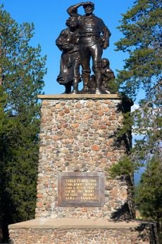 Three figures on a tall stone plinth