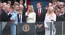 Trump, with his family watching, raises his right hand and places his left hand on the Bible as he takes the oath of office. Roberts stands opposite him administering the oath.