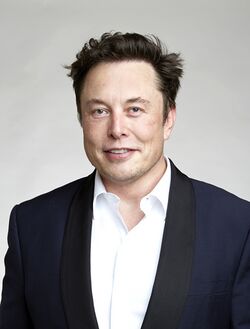 An image of Musk smiling in a suit, sans tie
